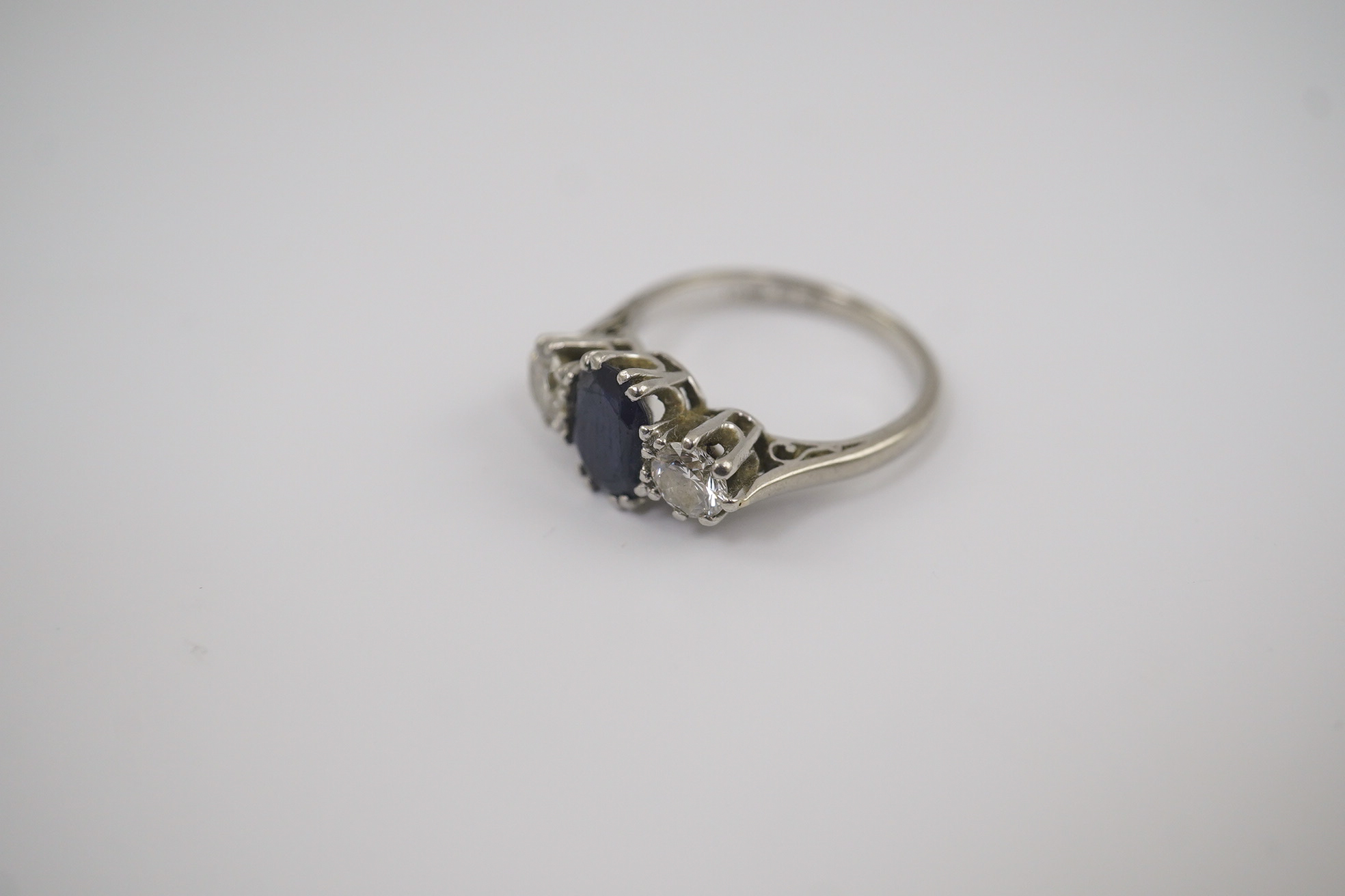 An 18ct white gold and platinum, single stone oval cut sapphire and two stone round cut diamond set ring